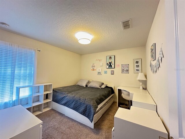 bedroom with dark colored carpet and a textured ceiling