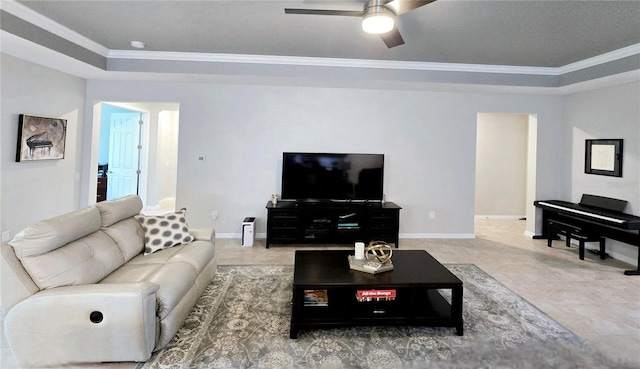 tiled living room featuring a raised ceiling, ornamental molding, and ceiling fan