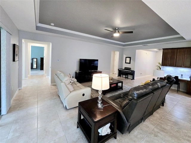 tiled living room with ceiling fan, ornamental molding, a tray ceiling, and a textured ceiling