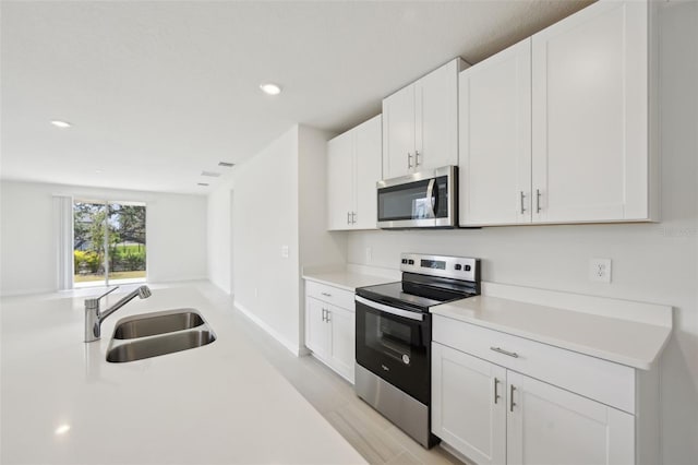 kitchen with appliances with stainless steel finishes, white cabinetry, and sink