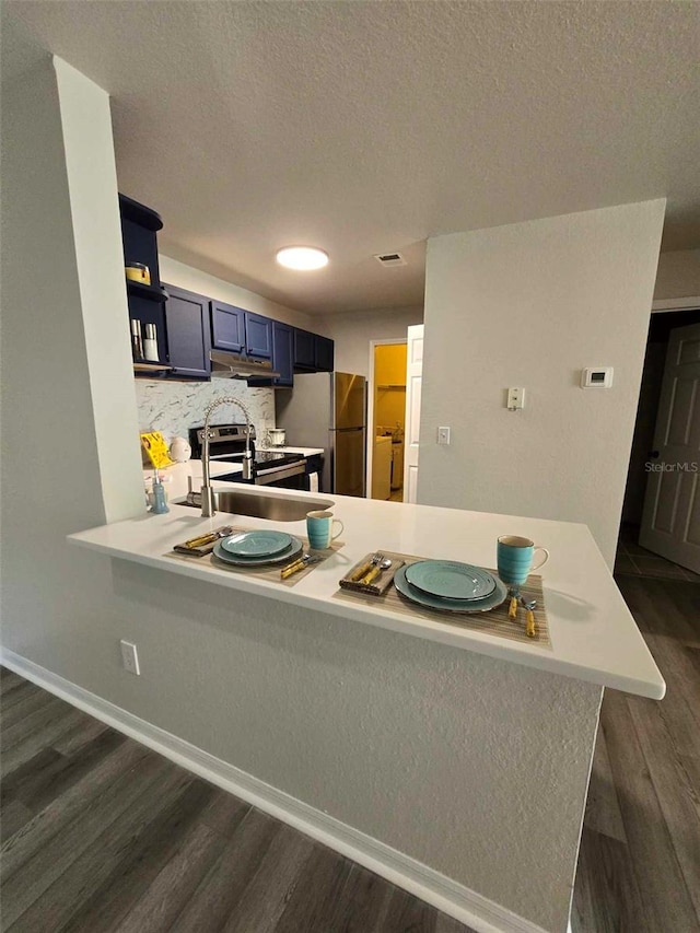 kitchen featuring kitchen peninsula, blue cabinetry, dark hardwood / wood-style flooring, and appliances with stainless steel finishes