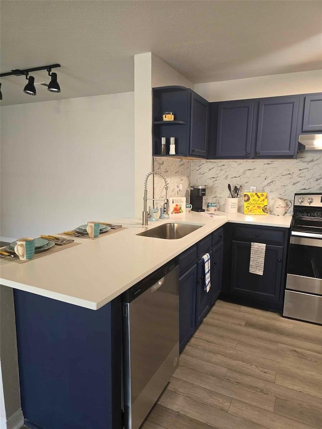 kitchen featuring light hardwood / wood-style floors, a kitchen breakfast bar, sink, kitchen peninsula, and stainless steel appliances