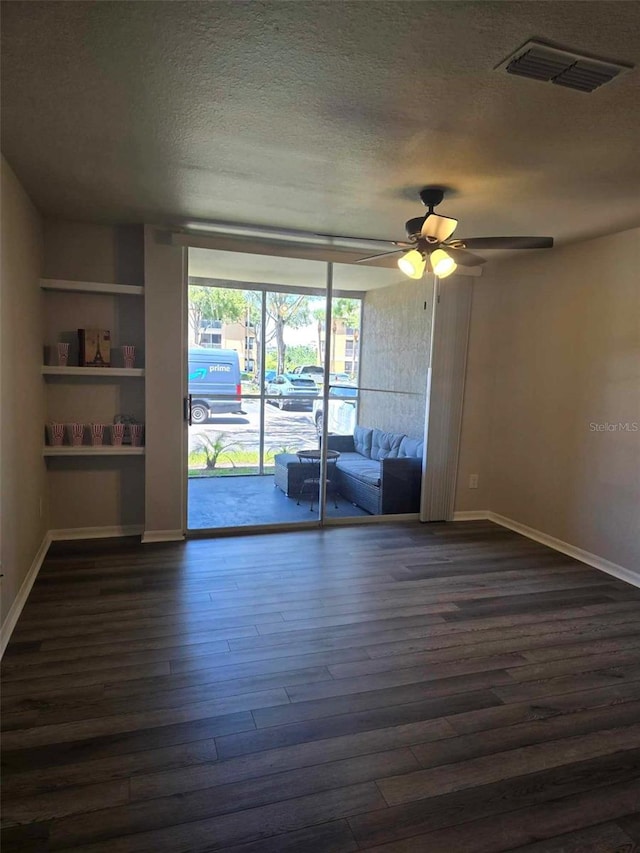 unfurnished room featuring built in shelves, a textured ceiling, dark hardwood / wood-style floors, and ceiling fan