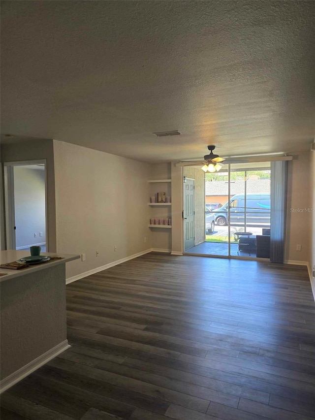 unfurnished living room with ceiling fan, dark wood-type flooring, and a textured ceiling