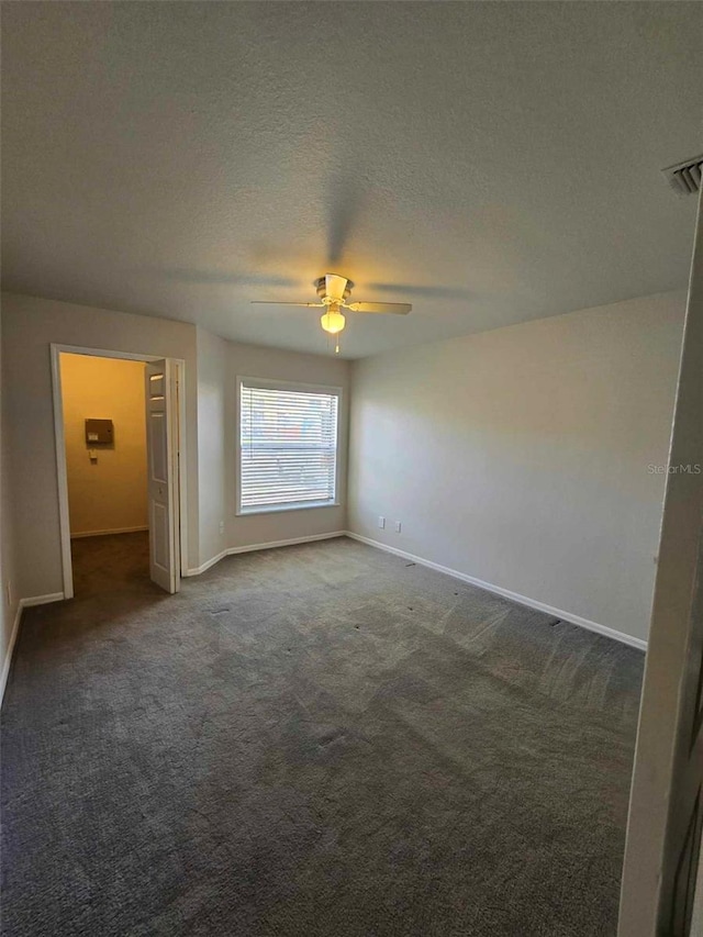 unfurnished bedroom with ceiling fan, dark carpet, and a textured ceiling