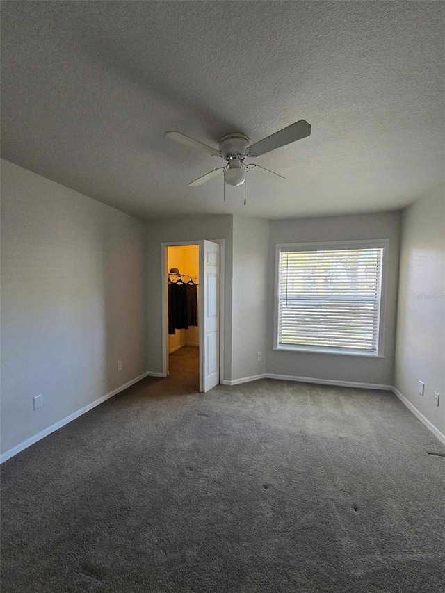 unfurnished bedroom with ceiling fan, carpet flooring, a closet, and a spacious closet