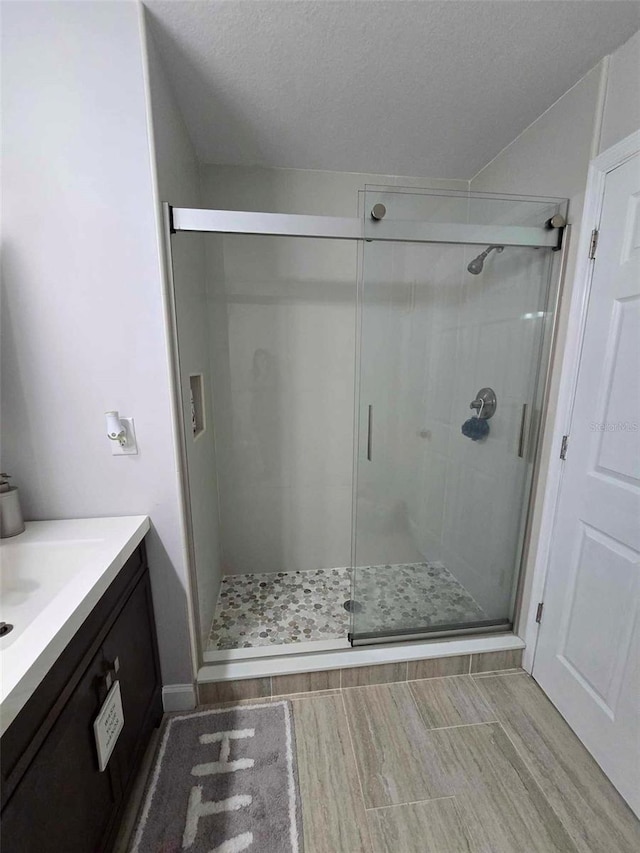 bathroom with a textured ceiling, an enclosed shower, and vanity