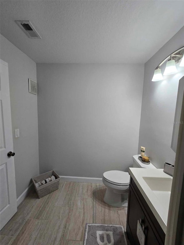 bathroom featuring a textured ceiling, toilet, and vanity