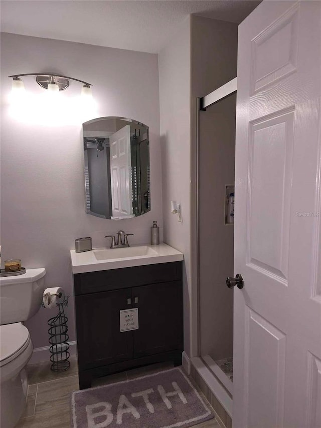 bathroom with toilet, walk in shower, and vanity