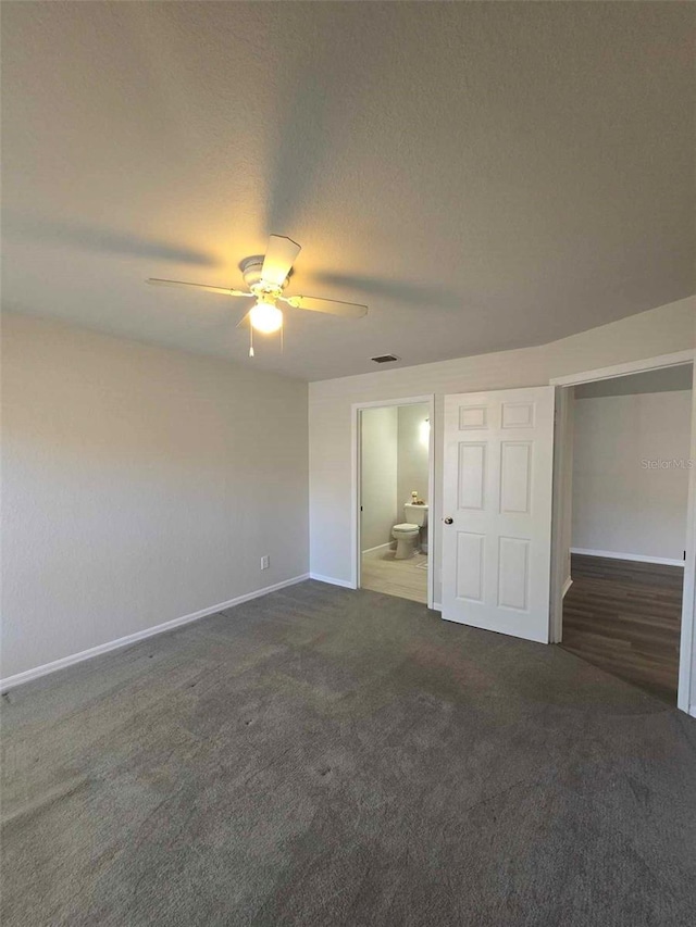 unfurnished bedroom with dark colored carpet, connected bathroom, ceiling fan, and a closet