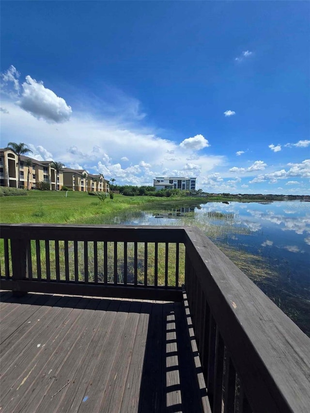 wooden terrace featuring a lawn and a water view