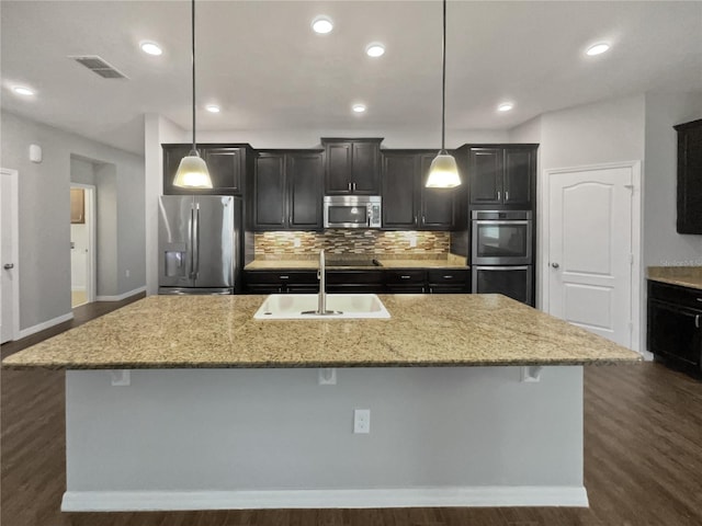 kitchen with sink, appliances with stainless steel finishes, an island with sink, a kitchen bar, and decorative light fixtures