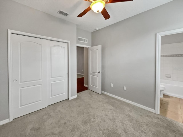 unfurnished bedroom featuring light colored carpet, a closet, ceiling fan, and ensuite bathroom