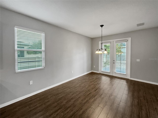 spare room featuring dark wood-type flooring, french doors, and a chandelier