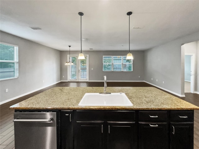 kitchen featuring hanging light fixtures, sink, and a center island with sink