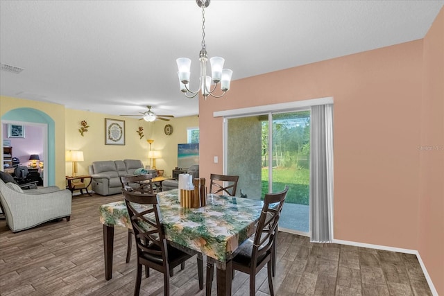 dining space with wood-type flooring and ceiling fan with notable chandelier