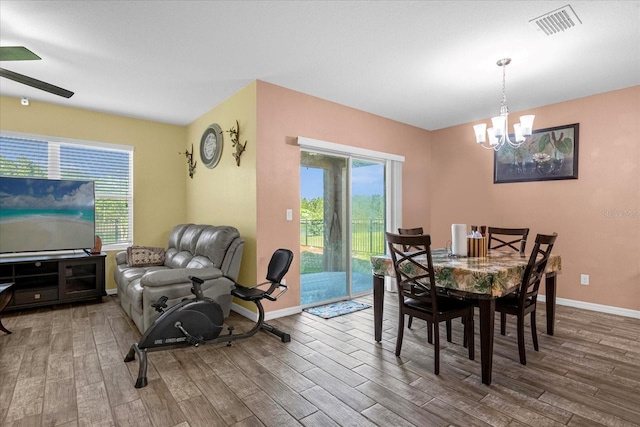 dining space with ceiling fan with notable chandelier and wood-type flooring