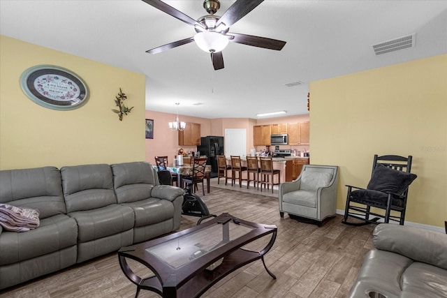 living room with ceiling fan with notable chandelier and wood-type flooring