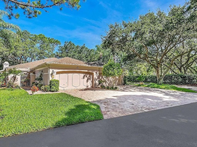 view of front of home featuring a garage, a front yard, decorative driveway, and stucco siding