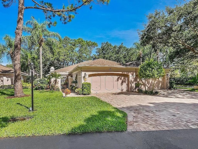 mediterranean / spanish-style home featuring a garage, stucco siding, decorative driveway, and a front yard