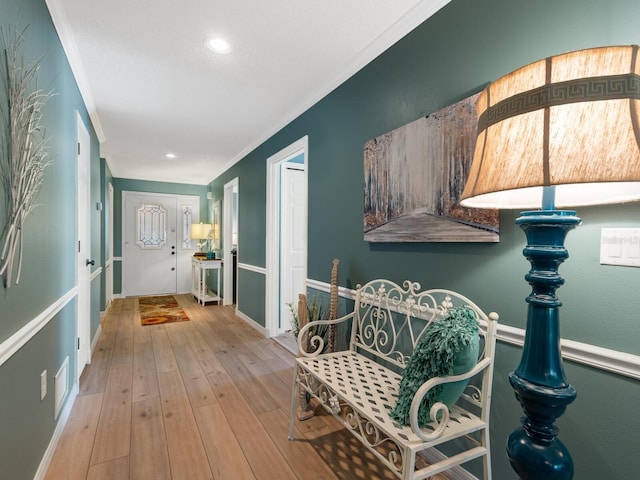 corridor with light wood-type flooring and ornamental molding