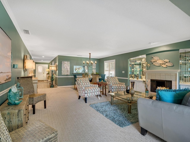 living area featuring carpet, crown molding, visible vents, a tiled fireplace, and a chandelier