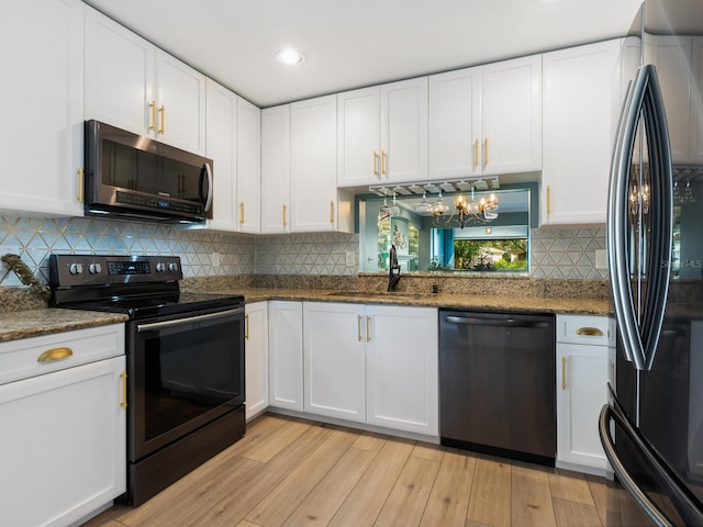 kitchen with light hardwood / wood-style flooring, dark stone counters, white cabinets, black appliances, and sink