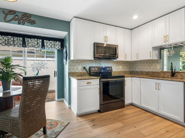 kitchen featuring plenty of natural light, white cabinetry, light wood-type flooring, and electric range