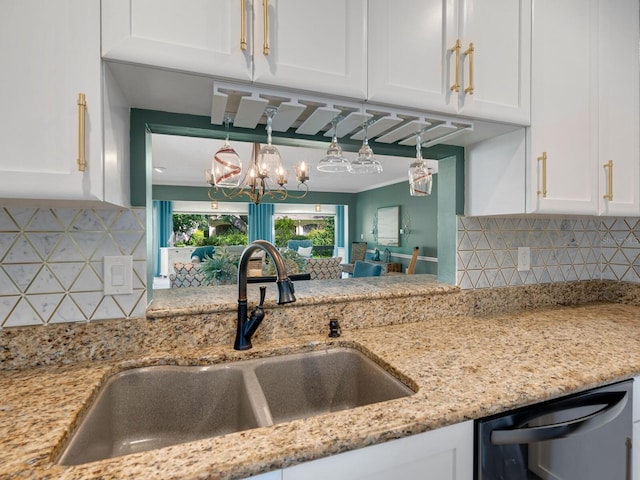 kitchen with tasteful backsplash, dishwashing machine, light stone countertops, white cabinetry, and a sink