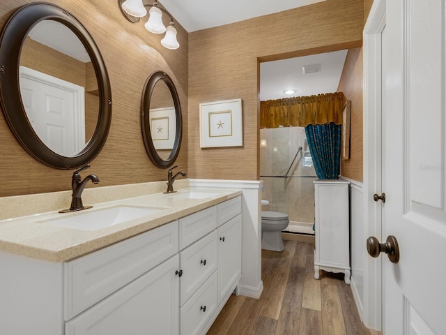 full bath with a sink, a shower stall, toilet, and wallpapered walls