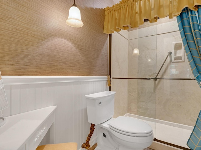 full bathroom featuring toilet, a wainscoted wall, and a tile shower