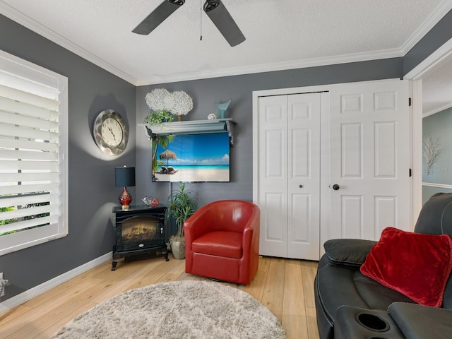 living area with light hardwood / wood-style flooring, a wood stove, crown molding, and ceiling fan