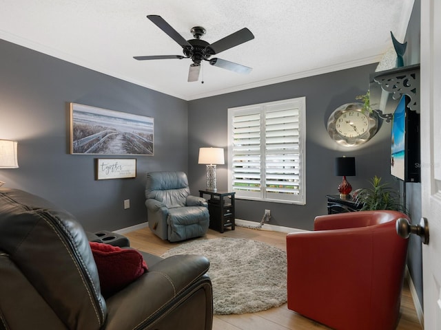 living area with crown molding, ceiling fan, a textured ceiling, wood finished floors, and baseboards