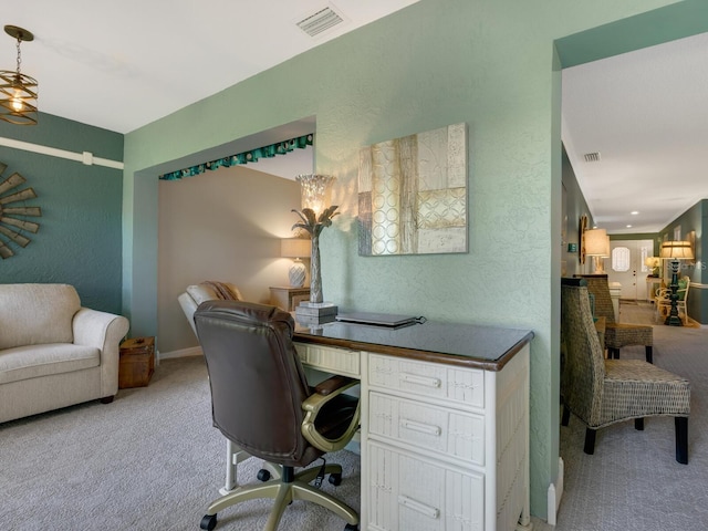 home office with a textured wall, carpet flooring, and visible vents