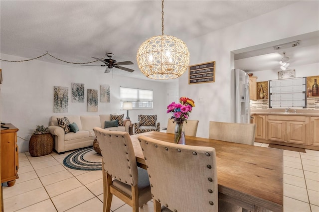 tiled dining space featuring sink and ceiling fan with notable chandelier