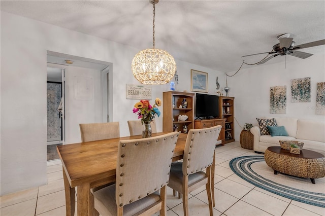 tiled dining area featuring a textured ceiling and ceiling fan with notable chandelier