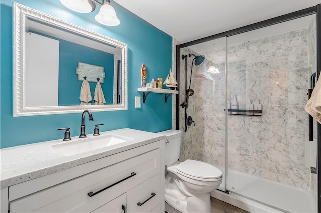 bathroom featuring a shower with door, toilet, and vanity