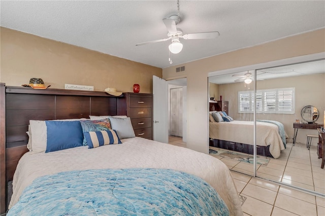 bedroom featuring a textured ceiling, ceiling fan, light tile patterned floors, and a closet