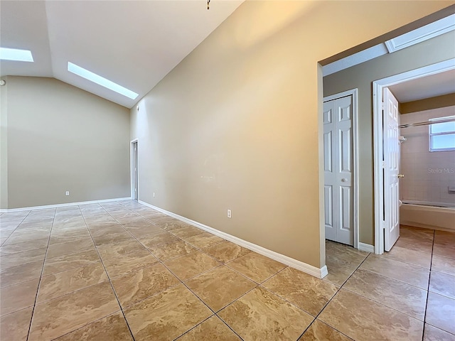 spare room with vaulted ceiling with skylight and light tile patterned floors