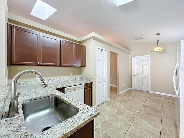 kitchen featuring light stone countertops, sink, white appliances, dark brown cabinets, and pendant lighting