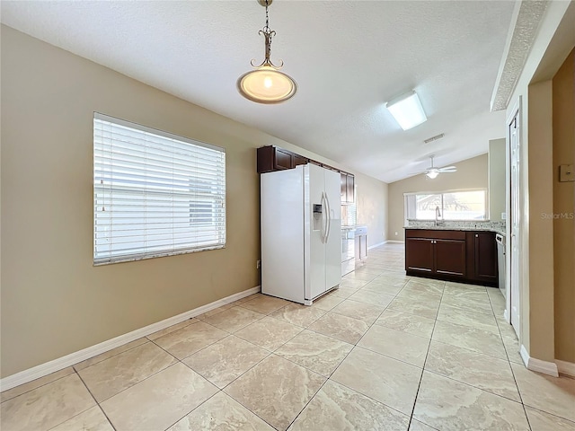 kitchen with white fridge with ice dispenser, dark brown cabinetry, vaulted ceiling, a textured ceiling, and light tile patterned flooring