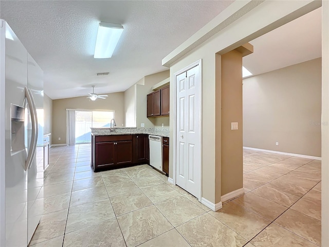 kitchen featuring white appliances, dark brown cabinetry, vaulted ceiling, sink, and kitchen peninsula