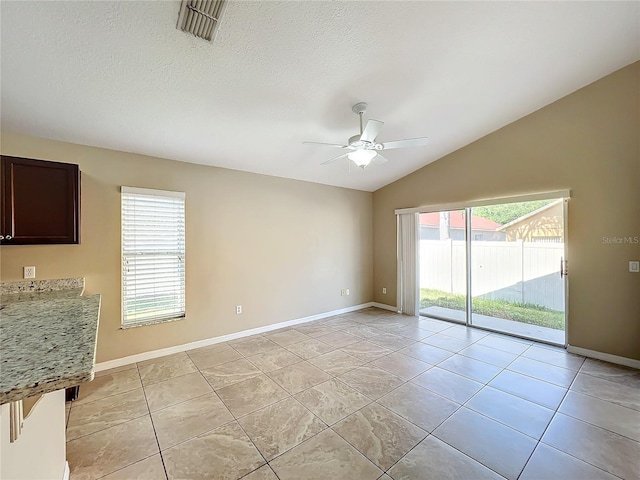 spare room with lofted ceiling, light tile patterned floors, ceiling fan, and a healthy amount of sunlight