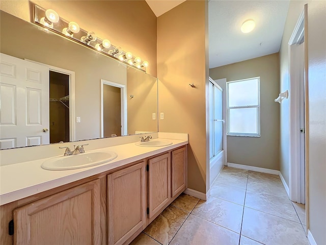 bathroom featuring vanity, bath / shower combo with glass door, and tile patterned flooring