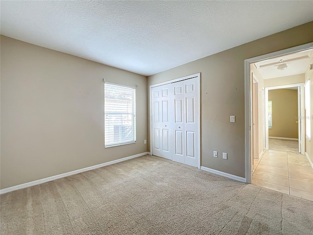 unfurnished bedroom featuring light carpet, a closet, and a textured ceiling