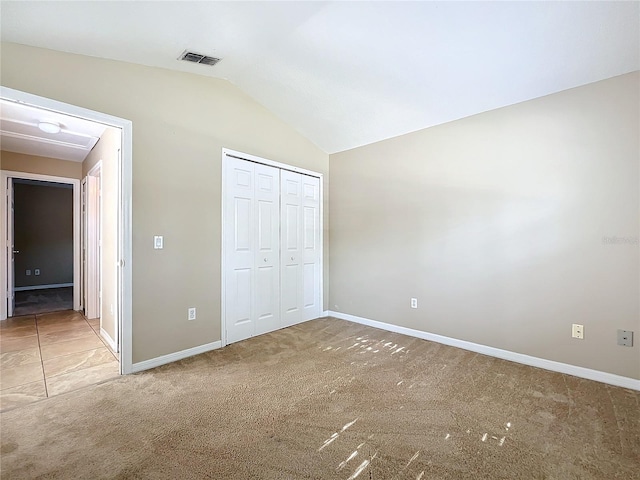 unfurnished bedroom with carpet floors, a closet, and vaulted ceiling