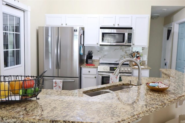 kitchen featuring decorative backsplash, appliances with stainless steel finishes, white cabinetry, and light stone countertops