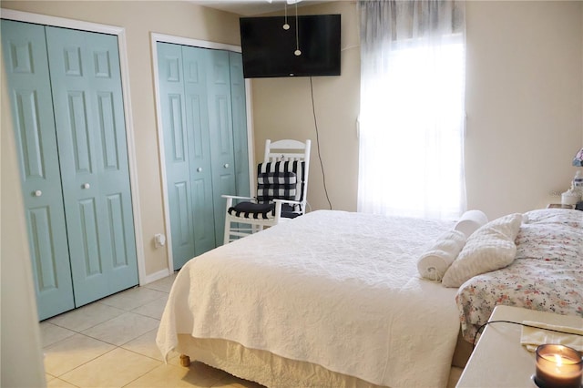 bedroom featuring light tile patterned flooring and multiple closets