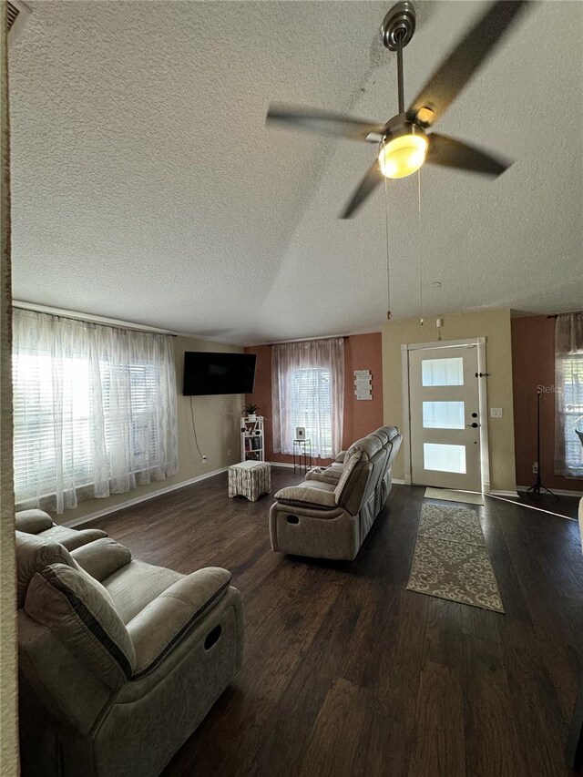 living room featuring ceiling fan, dark wood-type flooring, and a textured ceiling