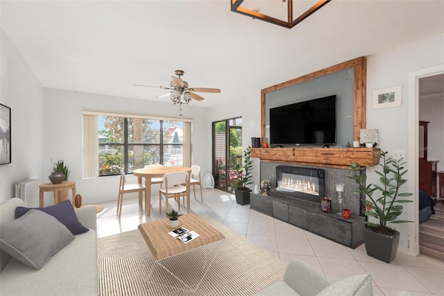 living room featuring ceiling fan, light tile patterned flooring, a fireplace, and radiator heating unit